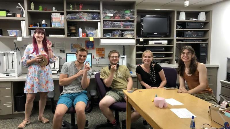 Four Summer Institute Students sitting and a Faculty Member standing in the Mudd Library Makerspace.